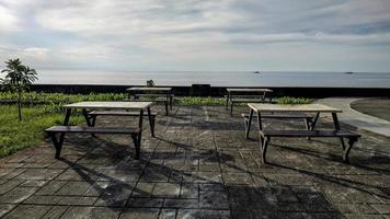 reihen minimalistischer stühle und tische zum entspannen am strand von anjungan vovasanggayu in der pasangkayu-regentschaft, indonesien, mit meereshintergrund foto