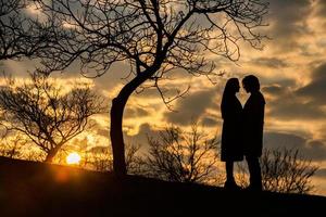 Silhouette eines romantischen Paares in Liebe, Mann und Frau im Sonnenunterganghimmel. Romantik der Beziehungen zwischen Liebespaaren im Garten foto