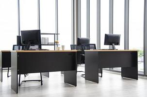moderne büroeinrichtung mit tisch, computer, monitor, großem glasfenster um den raum ohne menschen foto