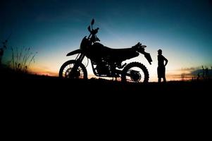 Herren-Silhouetten und Touren-Motocross-Bikes. Park zum Entspannen in den Bergen am Abend. abenteuerreise- und freizeitkonzept foto