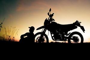 Herren-Silhouetten und Touren-Motocross-Bikes. Park zum Entspannen in den Bergen am Abend. abenteuerreise- und freizeitkonzept foto