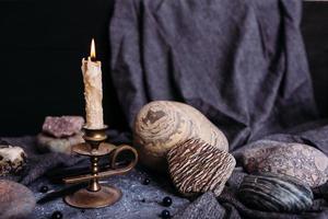 Brennende Kerze und Steine auf dem Hexentisch. okkultes, esoterisches Konzept. foto