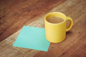 leere Notiz und Kaffeetasse auf Holztisch foto