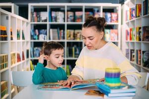 Mutter und ihr kleines Kind, der Sohn im Vorschulalter, lesen gemeinsam Kinderbücher foto