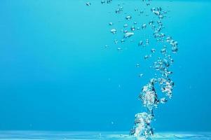 abstraktes Hintergrundbild von Blasen im Wasser. sauberes wasser mit wassertropfen und wellen. frisches wasser ein glas mit blasen blauem hintergrund. foto