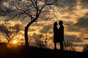 Silhouette eines romantischen Paares in Liebe, Mann und Frau im Sonnenunterganghimmel. Romantik der Beziehungen zwischen Liebespaaren im Garten foto