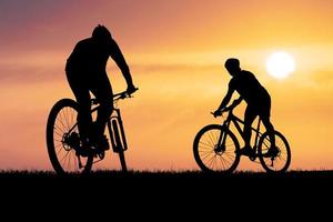 Silhouetten von Mountainbikes und Radfahrern am Abend fröhlich. reise- und fitnesskonzept foto
