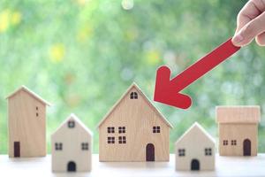 Hypothek, Frauenhand mit rotem Pfeildiagramm und Musterhaus auf natürlichem grünem Hintergrund, Unternehmensinvestitionen und Immobilienkonzept foto