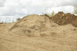 Sand auf der Baustelle. Baumaterial wird auf Haufen gestapelt. foto