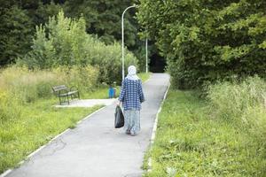 Frau mit Tasche geht durch den Park. Mädchen im Park. Mann auf der Straße. entlang der Straße gehen. foto