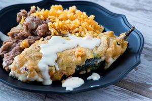 Mexikanische Chili Relleno mit Bohnenmus und spanischem Reis auf Teller foto