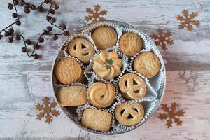 Sortiment von Weihnachtsplätzchen in runder Dose in festlicher Umgebung flach gelegt foto