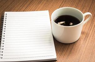 leeres Notizbuch und Kaffee auf Holztisch foto