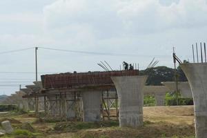 Bau und Gießen von Betonsäulen, um das Gewicht der Schnellstraßenbrücke zu tragen - im Bau, um die Brückenstruktur zu unterstützen, die von Bauingenieuren kontrolliert wird, um Reisen zu reduzieren foto