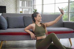 junge fitnessfrau in sportbekleidung mit smartphone beim trainieren zu hause, gesund und lebensstil. foto