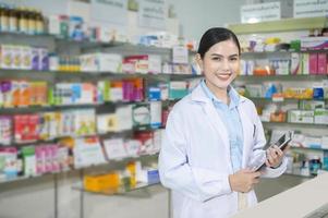 Porträt der Apothekerin mit Tablet in einer modernen Apotheke Drogerie. foto