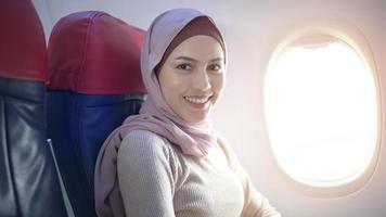 junge muslimische frau, die hijab trägt, nutzt smartphone an bord, reise- und urlaubskonzept foto