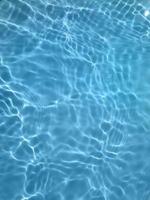 defocus verschwommenes blaues wasser im schwimmbad geplätscherter wasserdetailhintergrund. Wasseroberfläche im Meer, Ozeanhintergrund. Wasser ist anorganisch, transparent, geschmacklos, geruchlos und nahezu farblos. foto