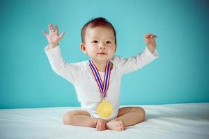 asiatisches baby mit goldener münze wie der gewinner, gesundes kind mit neuem familienkonzept foto
