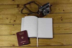 Leeres Reisetagebuch, Reisepass und altmodische Kamera auf einem Holztisch foto