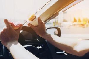 Mann, der Donuts und Kartoffelchips isst, während er Auto fährt - Multitasking-unsicheres Fahrkonzept foto