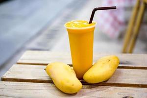 ein trinkfertiger Mango-Smoothie, daneben mit Mango dekorieren. foto