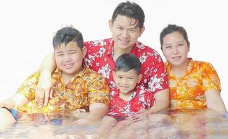 vierköpfige familie spielt wasser während des songkran festivals, dem traditionellen thailändischen neujahrsfest foto