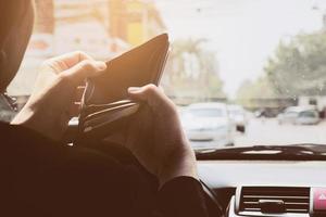 Mann schaut beim Autofahren auf seine leere Brieftasche, gefährliches Verhalten foto