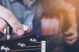 Mann, der Akustikgitarre stimmt foto