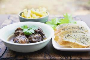 rindfleisch- und schweineintopf mit pommes frites und anderen lebensmittelrezepten auf holztisch, essensmahlzeiten, die zum essen bereit sind foto