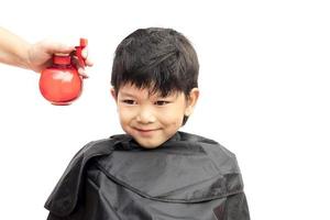 Ein Junge wird sein Haar vom Friseur isoliert auf weißem Hintergrund besprüht foto