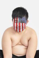 Lächeln Sie süßen dicken Jungen mit Overlay der amerikanischen Flagge auf seinem Gesicht, USA-Fan-Konzept. foto