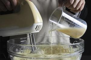 dame, die kuchencreme mit spachtel macht - hausgemachtes bäckereikochkonzept foto