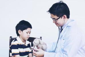 asiatischer Junge und Arzt während der Untersuchung mit Stethoskop auf weißem Hintergrund foto