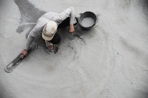 Arbeiter, der auf der Baustelle Straßenbeton gießt foto