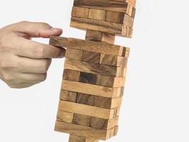 Schräges Holzblockturm-Jenga-Spiel mit Hand, Risikokonzept foto