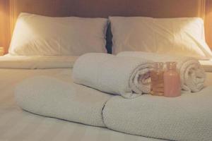 hotelhandtuch mit shampoo- und seifenflasche auf weißem bett foto