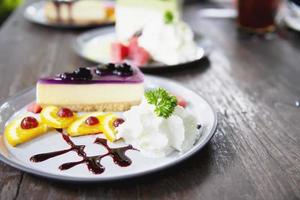 Bunte Käsekuchen Blaubeerbevorzugung mit gut dekorierten Fruchtstücken und Schlagsahne in weißer Platte - Kuchenrezeptmenükonzept foto