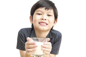 asiatischer Junge trinkt ein Glas Milch auf weißem Hintergrund foto