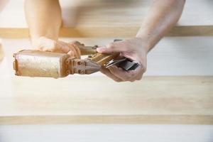 Zimmermann mit Luftnagelpistole bei Holzmöbelarbeiten foto