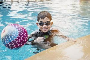 asiatisches glückliches kind, das im schwimmbad spielt foto