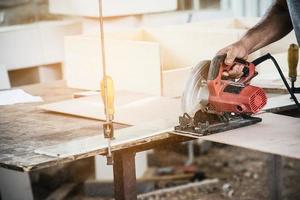 tischler, der mit der produktvorbereitung von holzmöbeln arbeitet, während er holzplatten mit einer kreissägemaschine schneidet foto