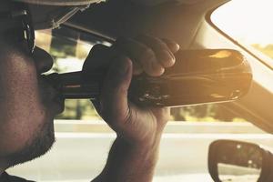 Mann trinkt Bier beim Autofahren foto