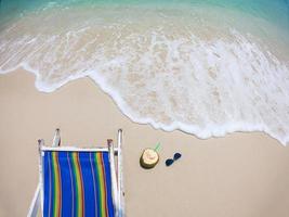 entspannen sie sich im strandkorb mit frischer kokosnuss auf einem sauberen sandstrand mit blauem meer und klarem himmel - meeresnaturhintergrund relaxkonzept foto