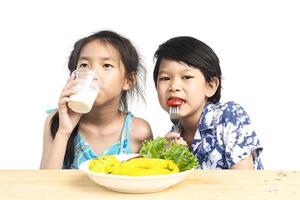 asiatische Jungen und Mädchen zeigen genießen Ausdruck mit frischem bunten Gemüse und Glas Milch isoliert auf weißem Hintergrund foto