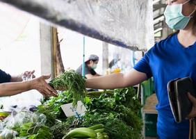 Frau kauft frisches Obst während der Covid-19-Ausbreitung auf dem lokalen Frischmarkt in Thailand foto