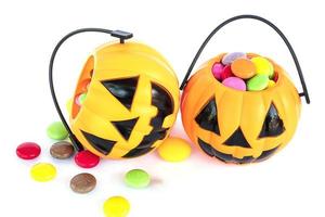 Halloween-Kürbis-Gesicht-Eimer mit bunten Süßigkeiten im Inneren isoliert über weiß foto
