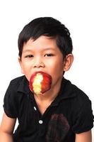 Porträt eines glücklichen Jungen, der Apfel auf weißem Hintergrund isst foto