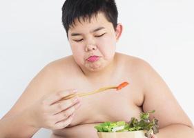 Ein dicker Junge hasst es, Gemüsesalat zu essen foto