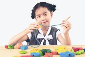 Schönes asiatisches Mädchen spielt buntes Holzblockspielzeug foto